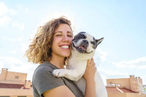 A woman is holding a dog on the roof.