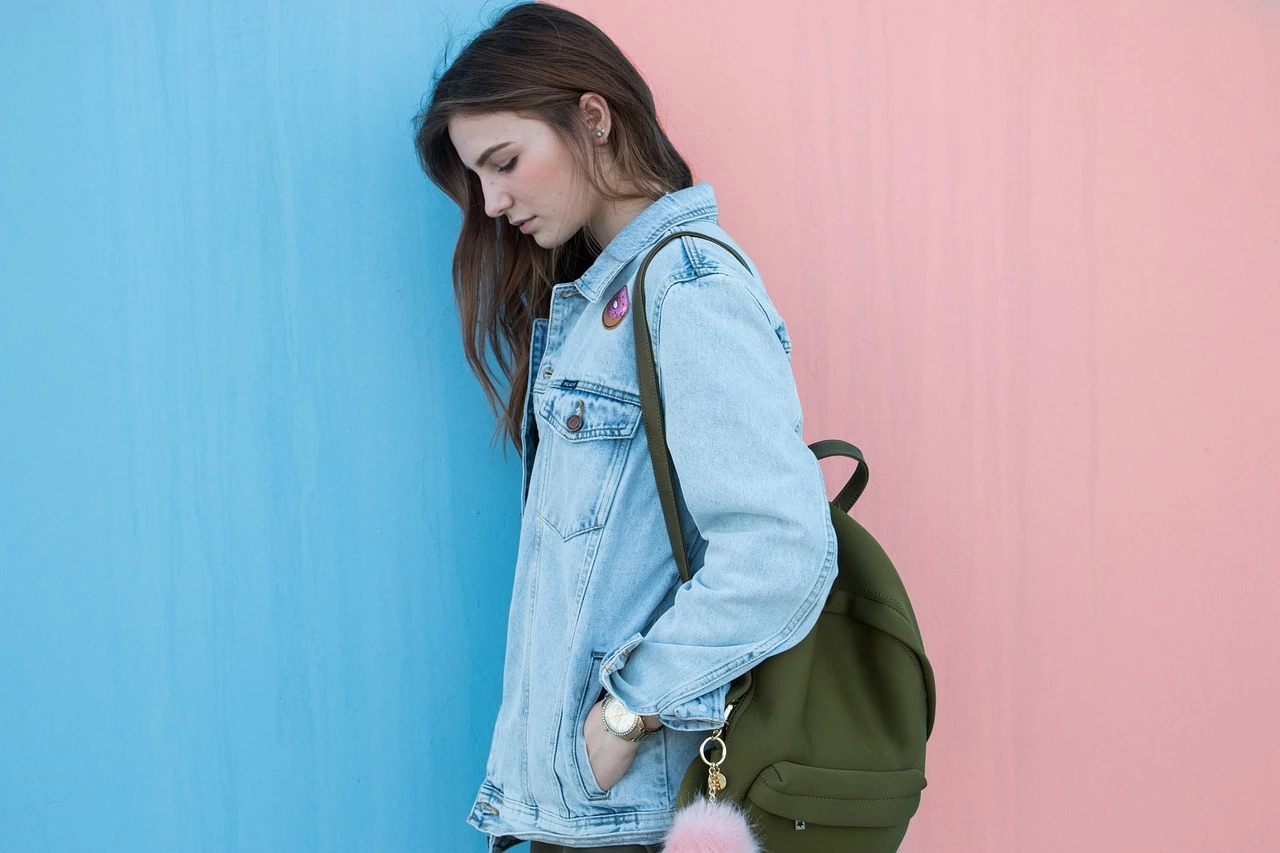 The girl stands before the blue-pink wall.